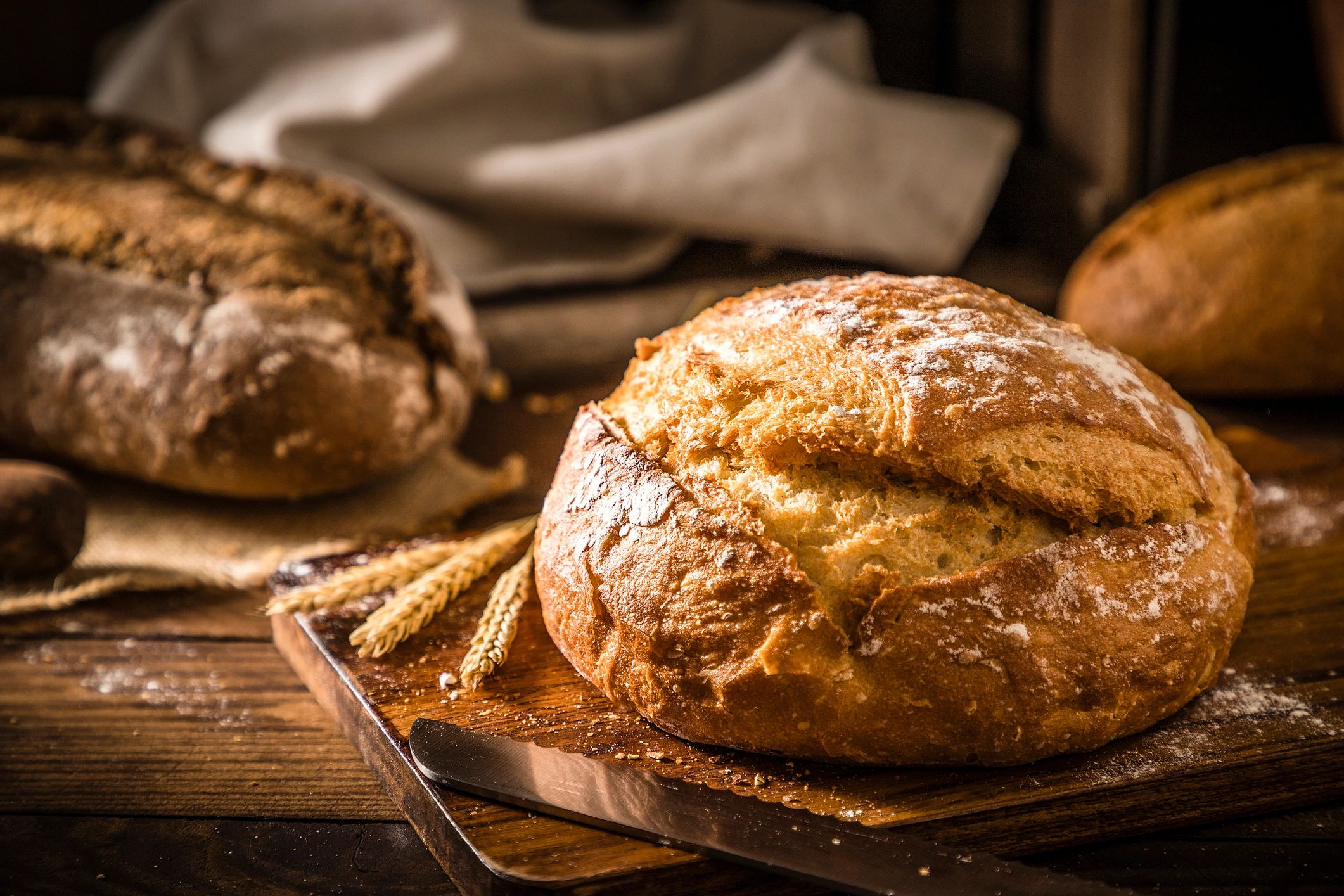 Rustic loaf of bread on a wooden table with wheat