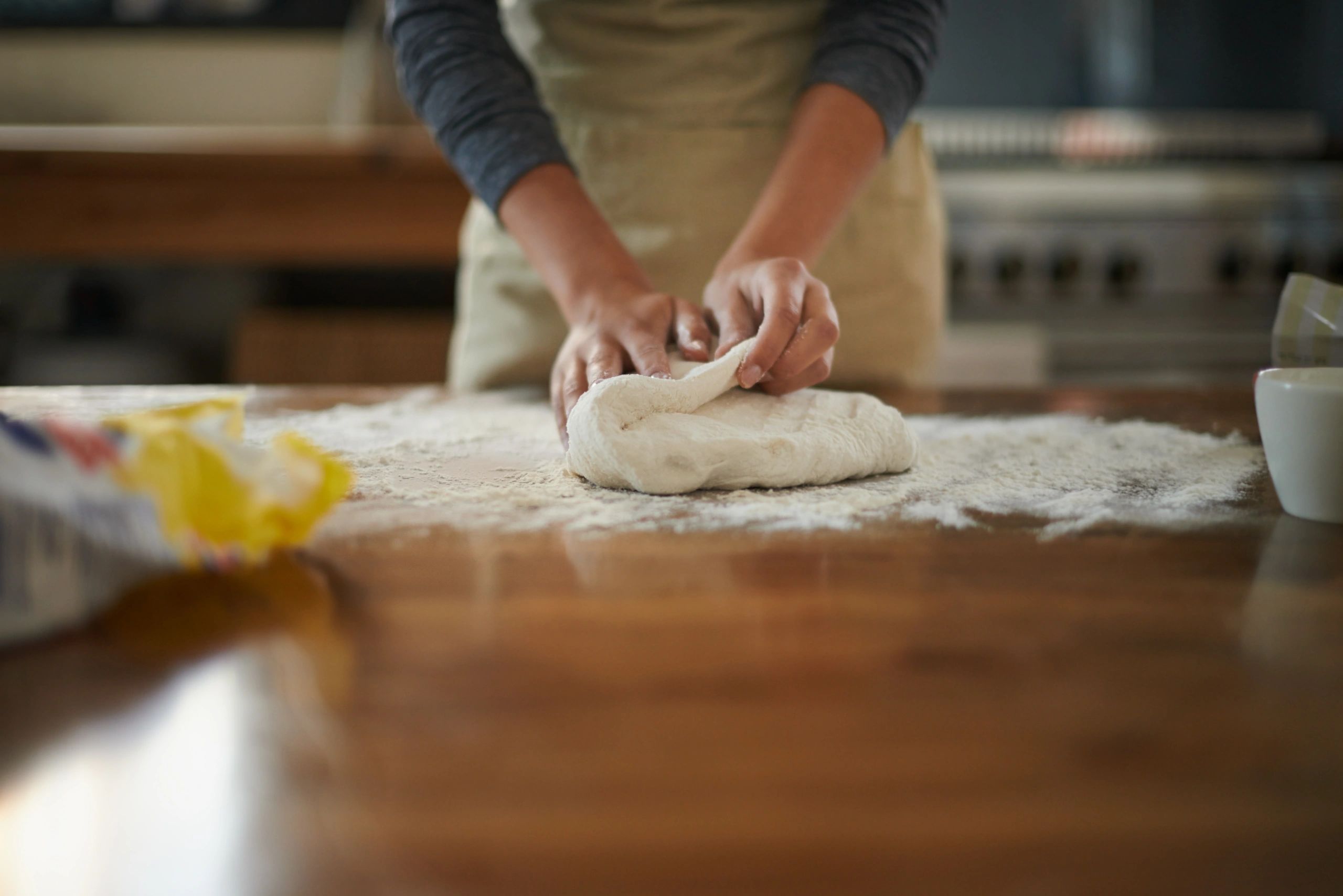 Hands kneading dough on a floured work surface