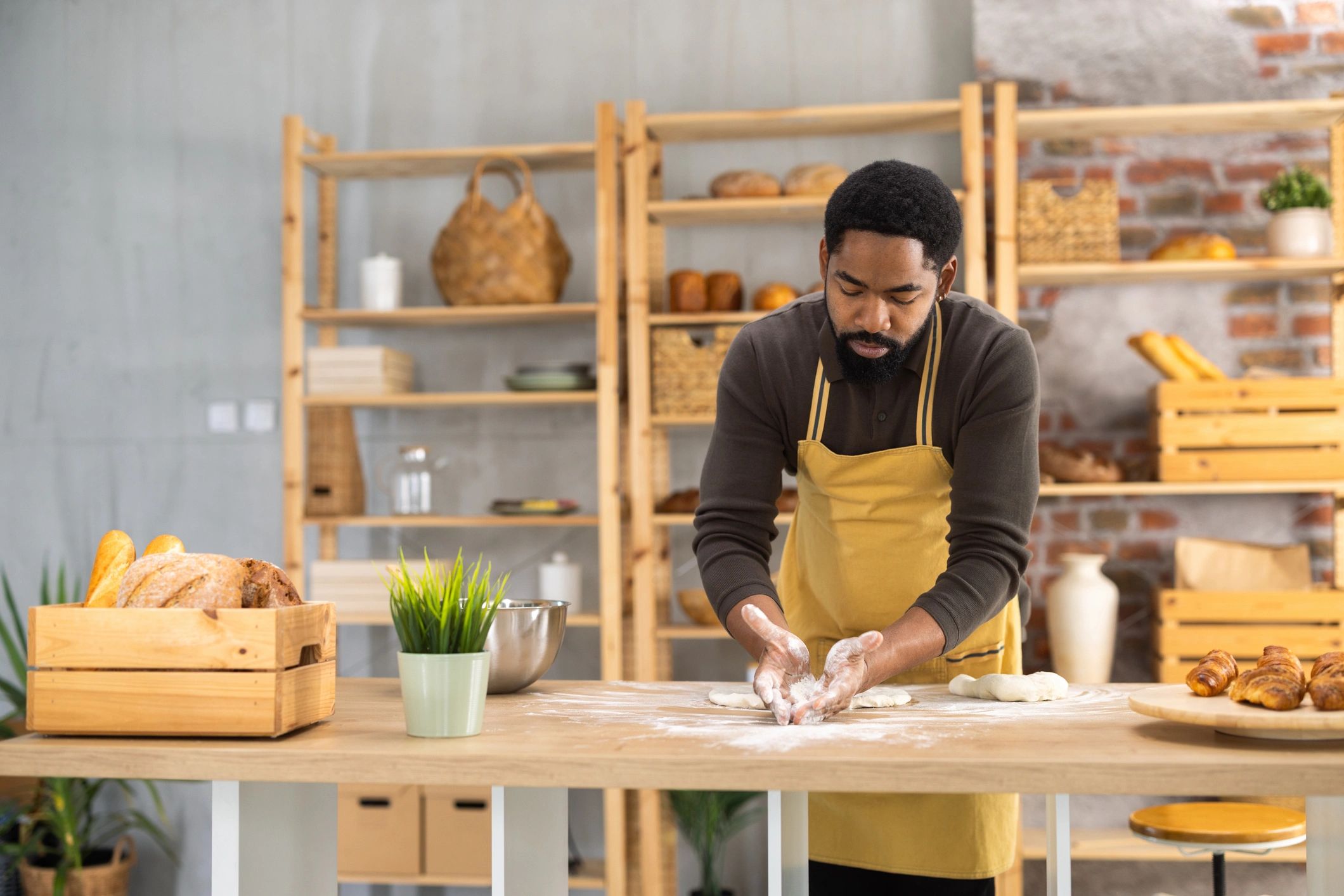 Baker preparing dough on a wooden table with flour